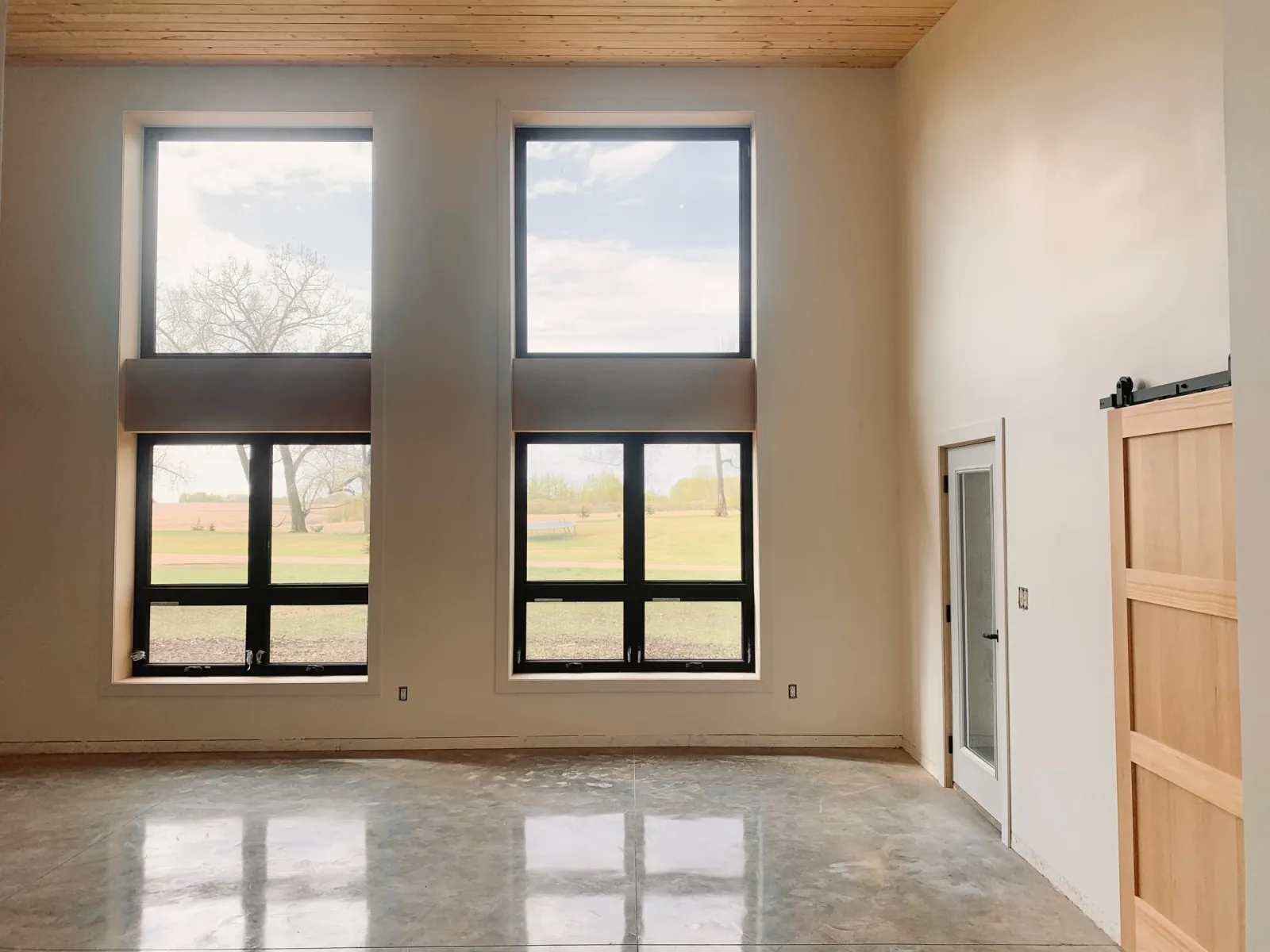 Open-plan room with tall windows, tongue and groove ceiling and a sliding barn door
