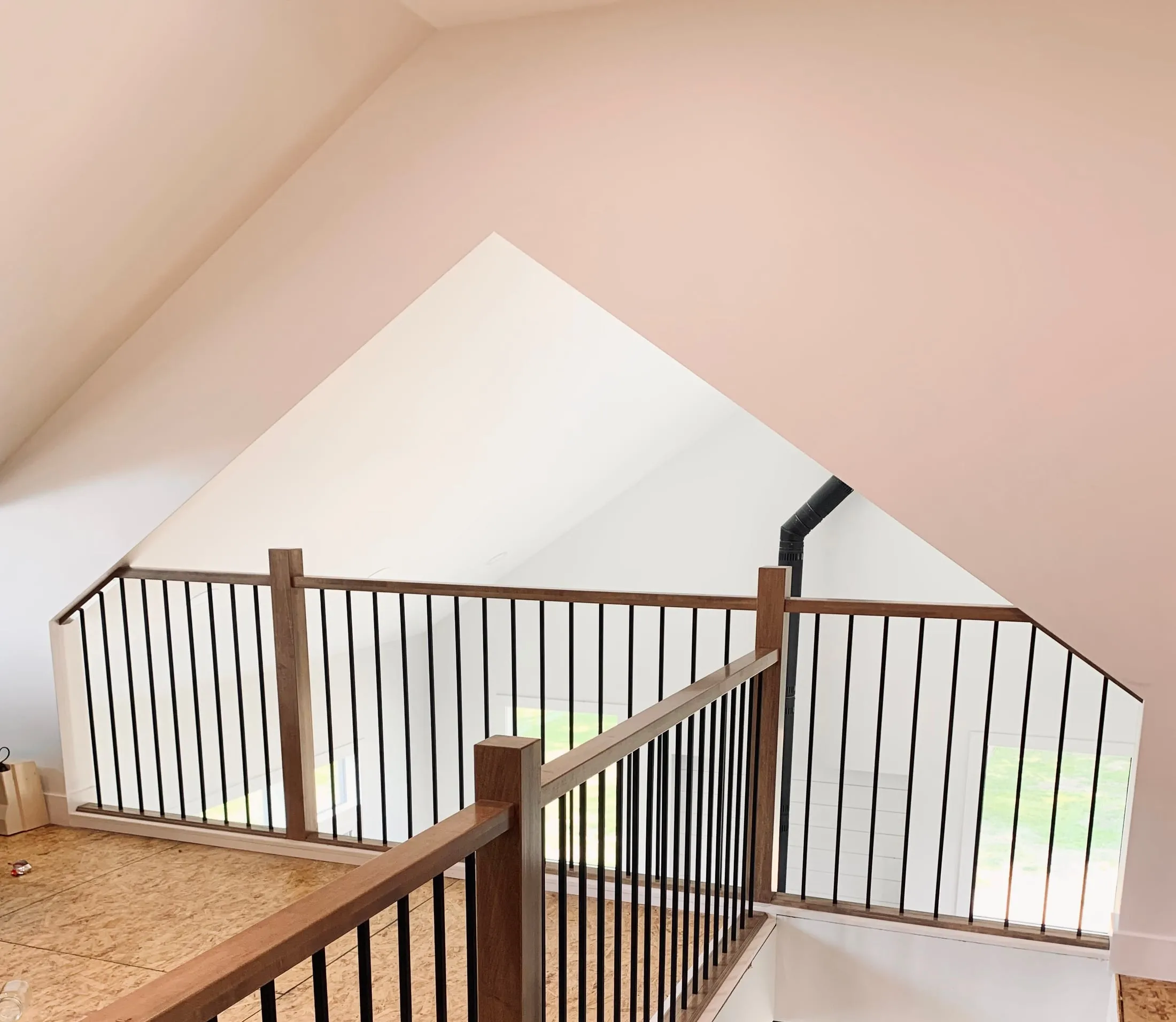 Loft railing with maple newel posts and iron spindles in a new home